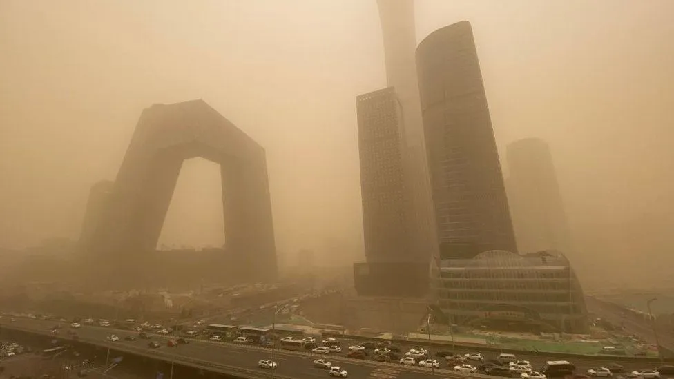 Residents of Xinjiang wander through a surreal, orange-tinted haze, as a severe sandstorm blankets cities, disrupting daily life and transportation. Sandstorms 