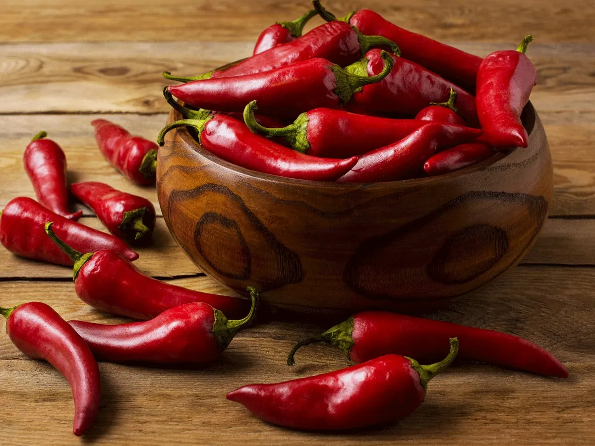 Close-up of vibrant red chili peppers on a rustic wooden table, highlighting their potential immune-boosting properties.