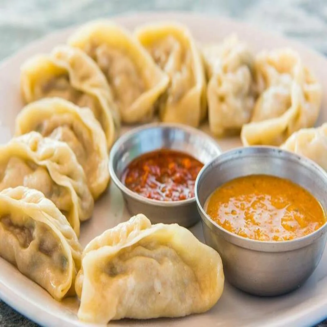 Chef expertly folding and pleating momo dough around a savory filling, creating perfectly shaped dumplings.